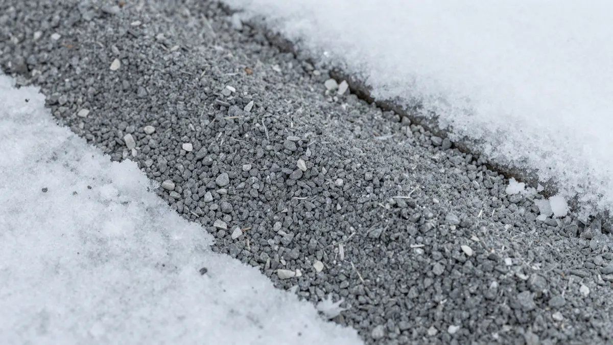 Abstumpfendes Streugut aus Granulat auf einem verschneiten Gehweg